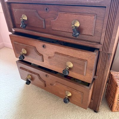 Vintage wooden three-drawer chest featuring fluted side columns, decorative drawer panels, and brass drop-pull hardware with dark handles.