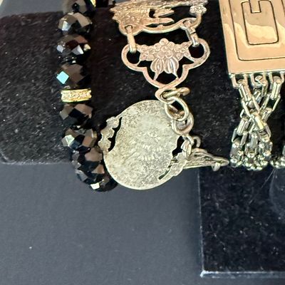 Selection of vintage fashion bracelets, including a faceted black bead stretch bracelet, an ornate silver-tone panel bracelet with a...