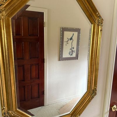 Vintage octagonal wall mirror featuring a gilded frame with ornate corner details.