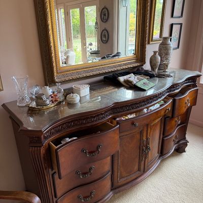 Ornate traditional wood credenza with a serpentine front, carved details, and a protective glass top, paired with a large matching...