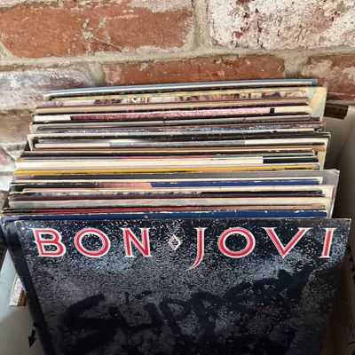 Stack of vintage vinyl records featuring Bon Jovi's 1986 album "Slippery When Wet" at the front, showing some wear on the...