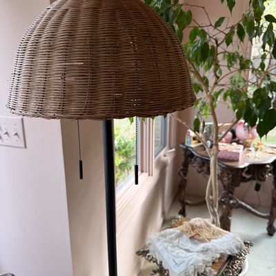 Vintage floor lamp featuring a woven wicker dome shade and a black metal pole with dual pull chain switches.