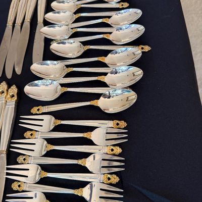 Royal Danish, vintage sterling silver flatware set featuring ornate gold-accented handles, including an assortment of spoons, forks, and...