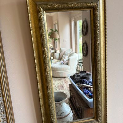 Rectangular wall mirror featuring an ornate, gold-finished frame with detailed scrollwork and a beaded outer edge.