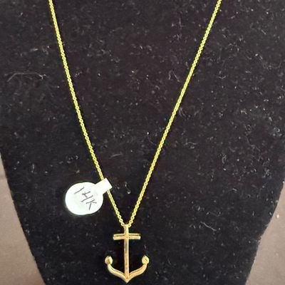 14k yellow gold anchor pendant on a delicate link chain, displayed on a black velvet bust.
