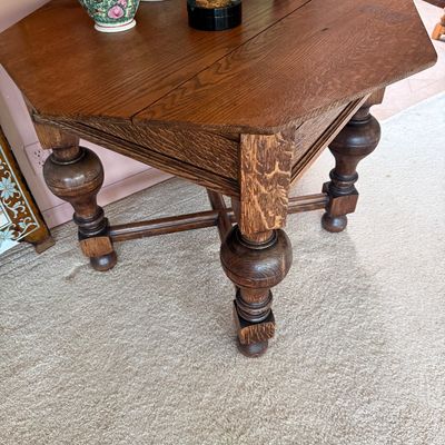 Antique oak envelope card table with a rotating, folding top and heavy bulbous turned legs connected by an X-stretcher.