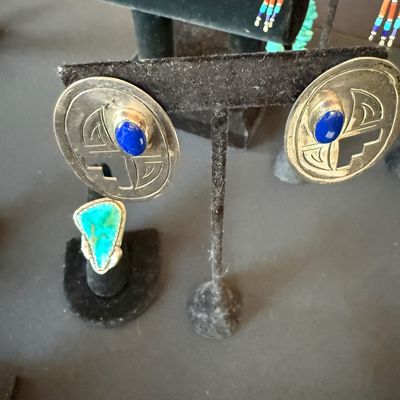 Southwestern sterling silver oval earrings featuring lapis lazuli cabochons and geometric cutouts, displayed alongside a turquoise ring.