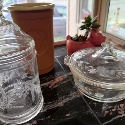Vintage etched glass kitchenware, including a tall lidded canister with floral and wheat motifs and a Fire-King lidded casserole dish...