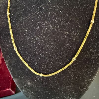 Gold braided chain necklace accented with small silver-tone beads, displayed on a black velvet bust.