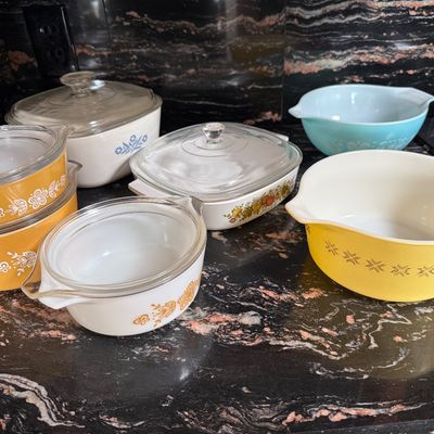 Collection of vintage Pyrex and CorningWare kitchenware, including mixing bowls and covered casserole dishes in various retro patterns...