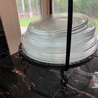 Stack of clear glass plates with textured concentric rings, displayed on a black wrought iron stand.
