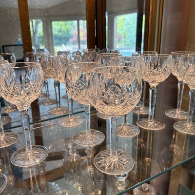 Collection of Waterford crystal wine glasses in the Lismore pattern, displayed on a glass shelf inside a mirrored cabinet.