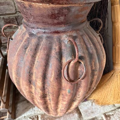 Rustic ribbed terracotta urn with a distressed, weathered finish and decorative metal ring handles.