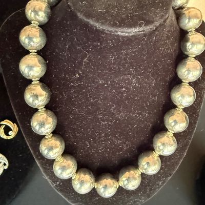 Vintage sterling silver bead necklace featuring large, polished spherical beads separated by small decorative spacers, displayed on a...