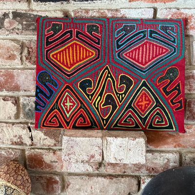 Vintage Panamanian Guna mola textile panel featuring vibrant geometric and stylized bird designs in red, yellow, green, and black.