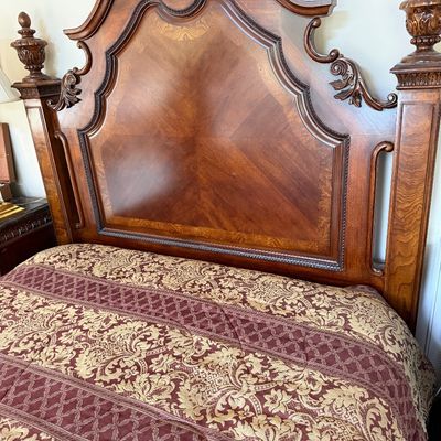Ornate traditional wooden headboard featuring a bookmatched veneer panel, carved scrollwork, and decorative finials, paired with a...