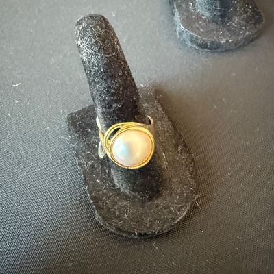 Mabe pearl ring set in a gold bezel on a silver-tone band, displayed on a black velvet ring stand.