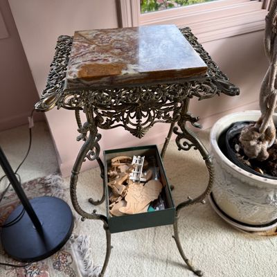 Ornate Victorian-style brass pedestal stand featuring a square polished onyx top and intricate openwork filigree detailing.