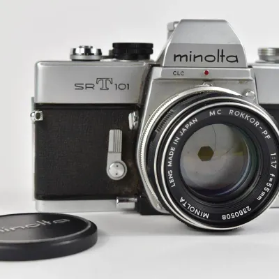 Vintage Minolta SR-T 101 35mm SLR film camera, equipped with a Minolta MC Rokkor-PF 55mm f/1.7 lens and matching lens cap.