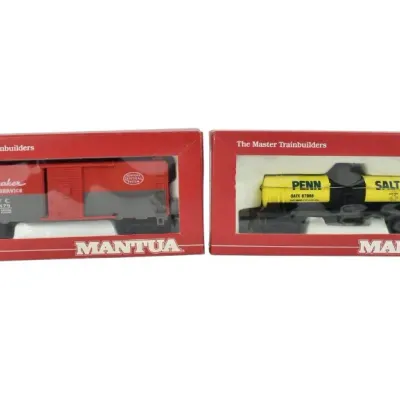 Two Mantua HO scale model train cars in their original boxes, including a red Pacemaker Freight Service boxcar and a yellow Penn Salt...