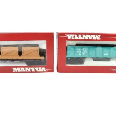 Two vintage Mantua HO scale model train cars in their original red boxes, including a Pennsylvania flatcar with crates and a teal...