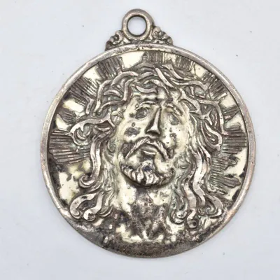 Vintage silver-tone religious medal depicting the face of Jesus Christ with a crown of thorns, showing some tarnish and wear.