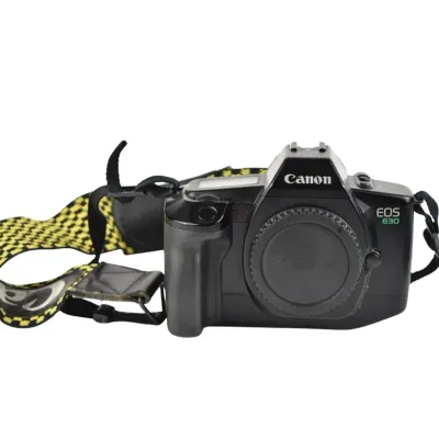 Canon EOS 630 35mm SLR film camera body with a body cap and a yellow and black patterned neck strap, circa late 1980s.