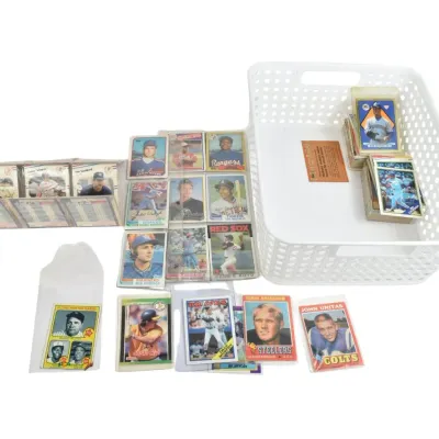 Collection of vintage sports trading cards, including baseball and football stars from the 1970s and 1980s, displayed alongside a white...