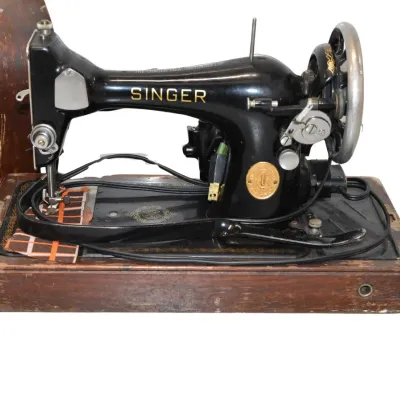 Vintage Singer electric sewing machine with a black cast-iron body, gold lettering, and a wooden base, accompanied by its original...