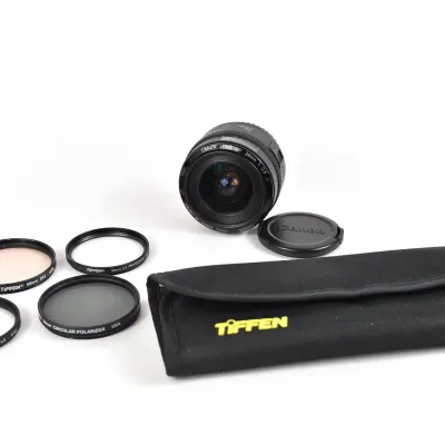Canon EF 28mm f/2.8 camera lens with front cap, accompanied by a Tiffen filter pouch and four assorted lens filters.