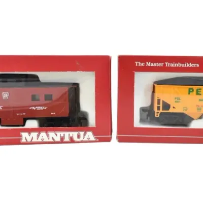 Two Mantua HO scale model train cars in their original red boxes, featuring a Pennsylvania caboose and a Peabody hopper car.