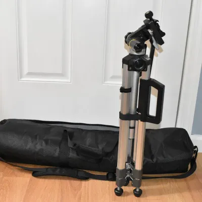 Aluminum camera tripod with a pan-and-tilt head, integrated carrying handle, and a black zippered canvas carrying bag.