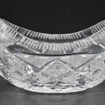 American Brilliant Period cut glass banana bowl, featuring intricate starburst and crosshatch patterns with a curved, scalloped rim.