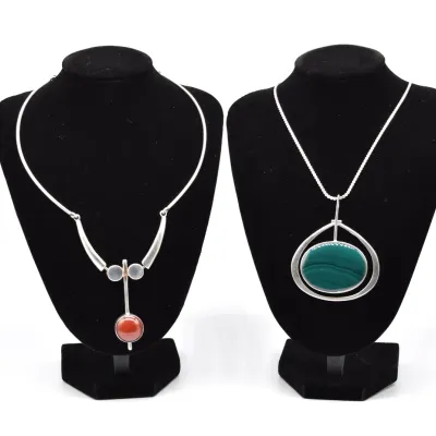 Two mid-century modern sterling silver necklaces, one featuring a carnelian drop pendant on a collar chain, and the other a large...
