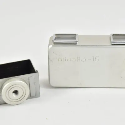 Vintage Minolta-16 subminiature camera with a matching silver-tone accessory attachment, showing some light surface wear.