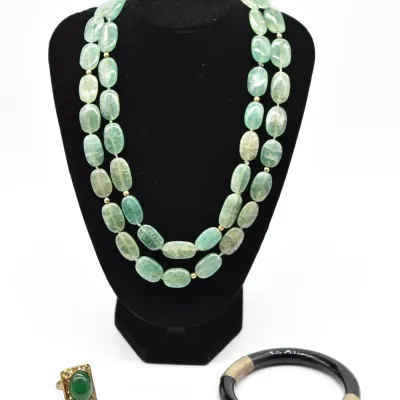 Two-strand light green fluorite or aventurine bead necklace displayed on a black bust, accompanied by a gold-tone ring with a green...