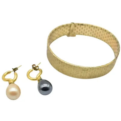 Gold-tone mesh bracelet paired with a mismatched set of pearl drop earrings in white and dark grey.