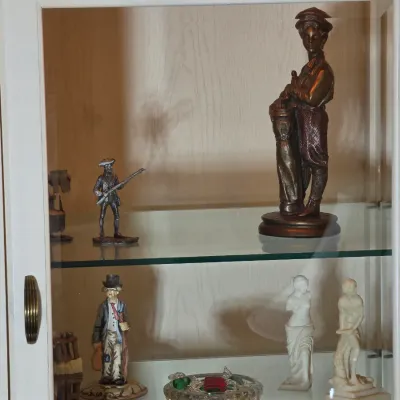 Collection of vintage decorative figurines, including a bronze-finish golfer statue, a pewter revolutionary soldier, and small...