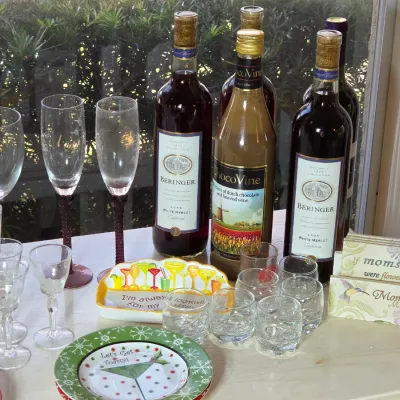 Assorted glassware, wine bottles including Beringer White Merlot and ChocoVine, decorative plates, and Mother's Day themed signs...