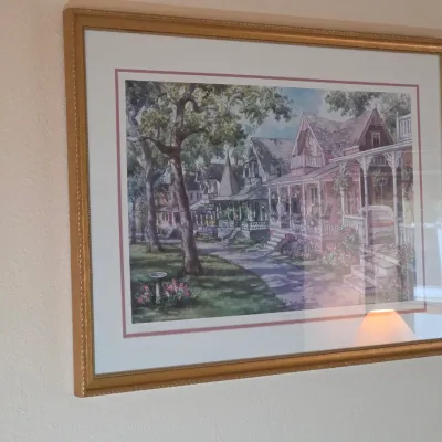 Framed and matted watercolor print depicting a row of Victorian-style cottage homes, housed in a decorative gold-finished frame.