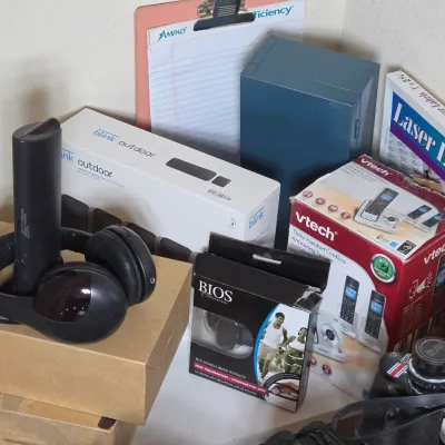 Assorted electronics and office supplies, including a boxed Blink Outdoor camera system, a VTech cordless phone system, a Bios Fitness...