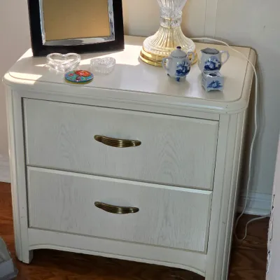 Two-drawer nightstand in a whitewashed oak finish with brass pulls, styled with a crystal lamp and small decorative items.