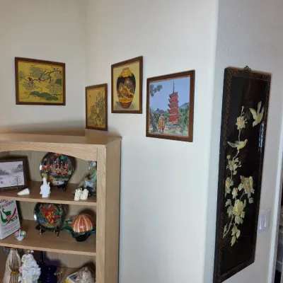 Collection of Asian-inspired wall art, including framed prints of pagodas and nature scenes, alongside a black lacquer panel with...