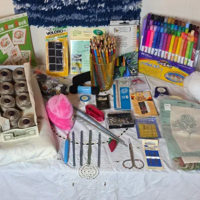 Assortment of crafting and sewing supplies, including crochet hooks, embroidery floss, colored pencils, markers, and needles.