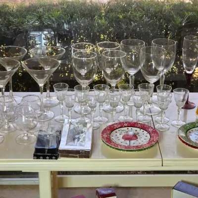 Assorted glassware collection including martini glasses, wine goblets, champagne flutes, and small cordial glasses, displayed alongside...