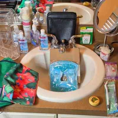 Assorted personal care and vanity items, including a blue gel face mask, Lands' End toiletry bags, hand sanitizers, oral hygiene...