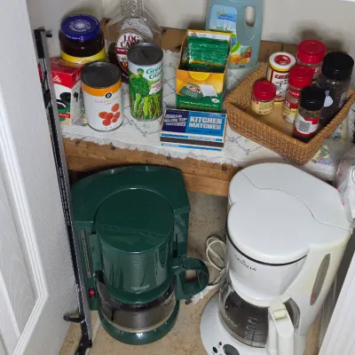 Assorted pantry items and coffee makers, including a green Connoisseur coffee maker, a white Gevalia coffee maker, canned goods, spices,...