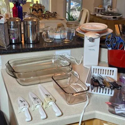 Assorted kitchenware including Pyrex baking dishes, a set of three white-handled knives with sheaths, a Black & Decker electric can...