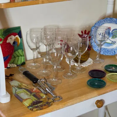 Assorted glassware and kitchen decor, including a set of clear wine glasses, a colorful parrot tile, a rooster plate, and small glass...