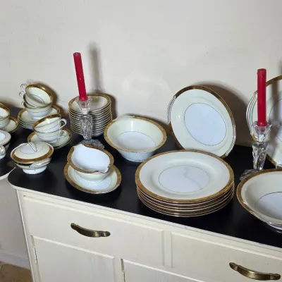 Vintage fine china dinnerware set with gold filigree borders, including plates, bowls, teacups, saucers, and serving pieces, displayed...